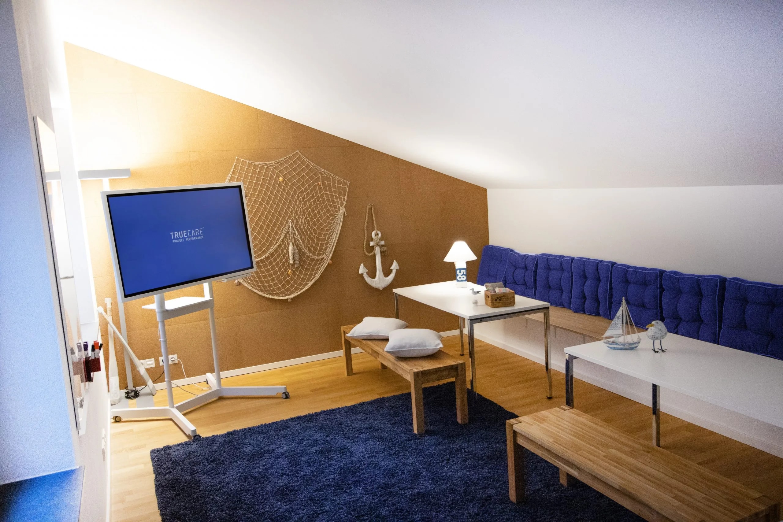 Workshopraum Hamburg in Hannover mit blauer Sitzbank, maritimer Wandgestaltung und Monitor