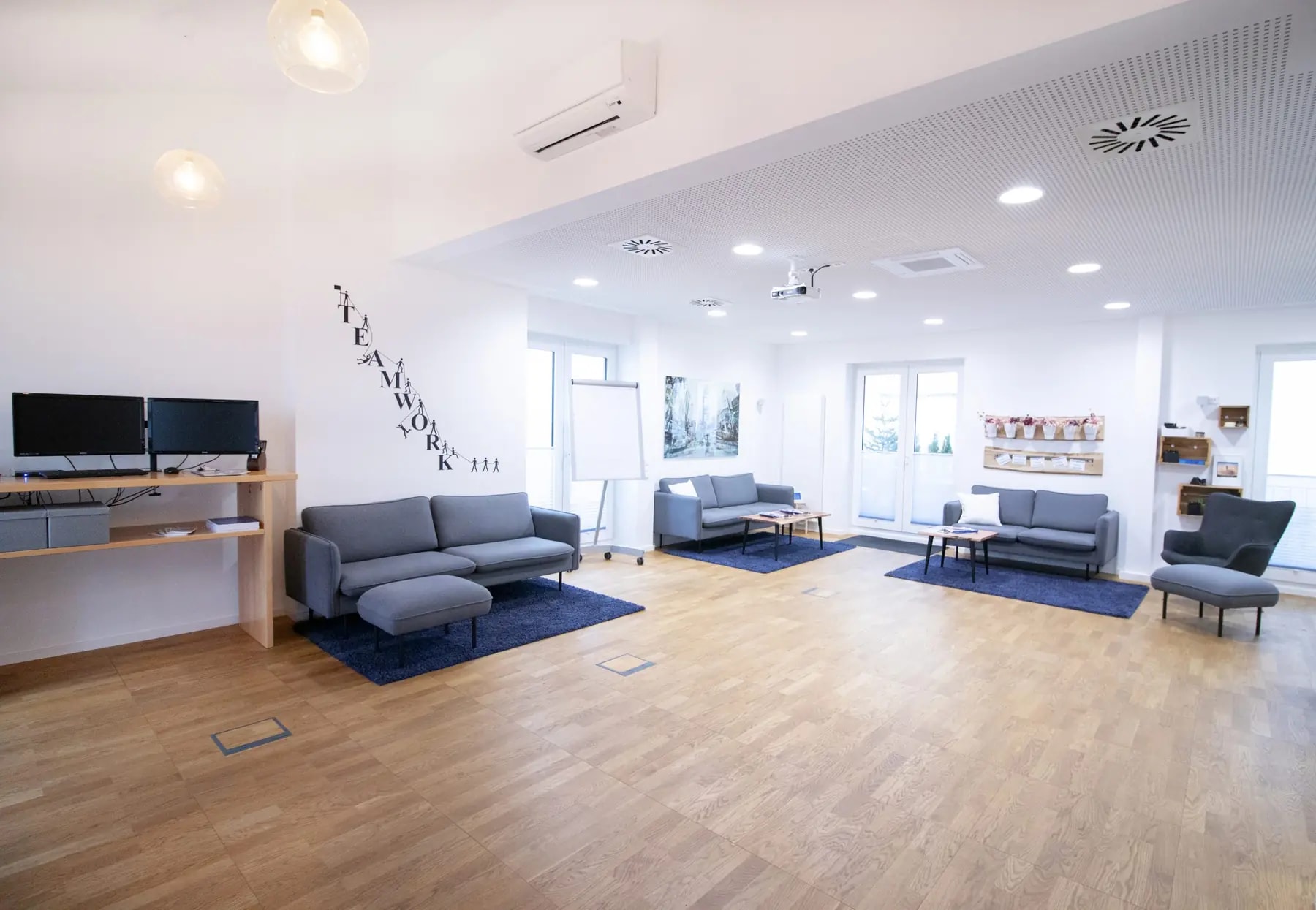 Seminarraum New York in Hannover mit Loungesofas, Monitor und Schriftzug Teamwork an der Wand
