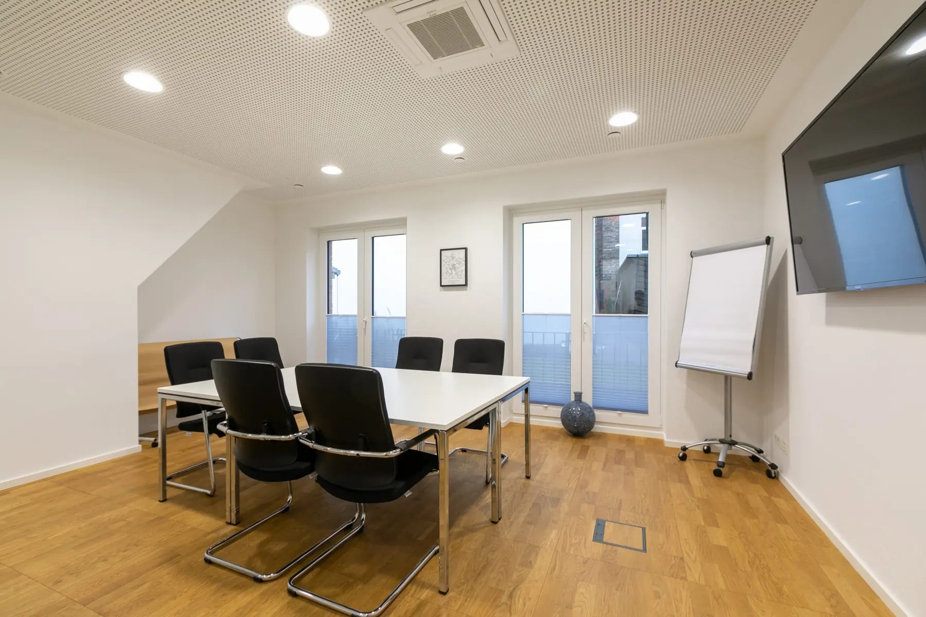 Trainingsraum Hannover mit Tisch, Freischwingern, Flipchart und Tür zur Terrasse