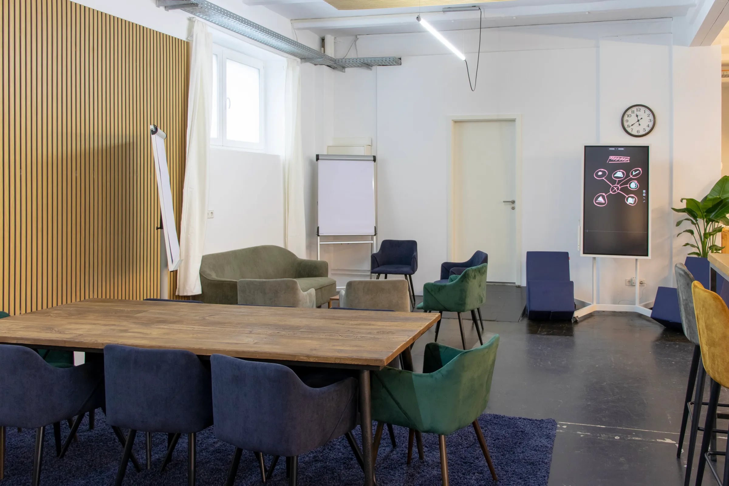 Großer Holztisch mit Stühlen, Flipchart und digitalem Flipchart im Maschinenraum Hannover
